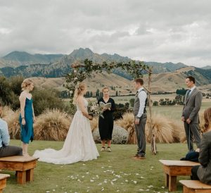 Wedding Ceremony for microwedding at The Lookout Lodge, Wanaka New Zealand. Wedding arch with mountains in the background, benches and Siobhain the Celebrant conducting Marriage photographed by Luisa Apanui Photography