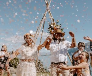 Bride & Groom walking hand in hand through confetti thrown by young girl. Lots of smiles